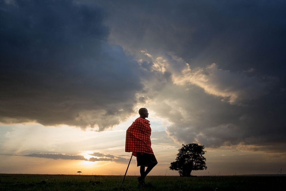 Josphat Mako, Maasai guide and companion to author and travel writer Stuart Butler stands as the sun begins to set over the…