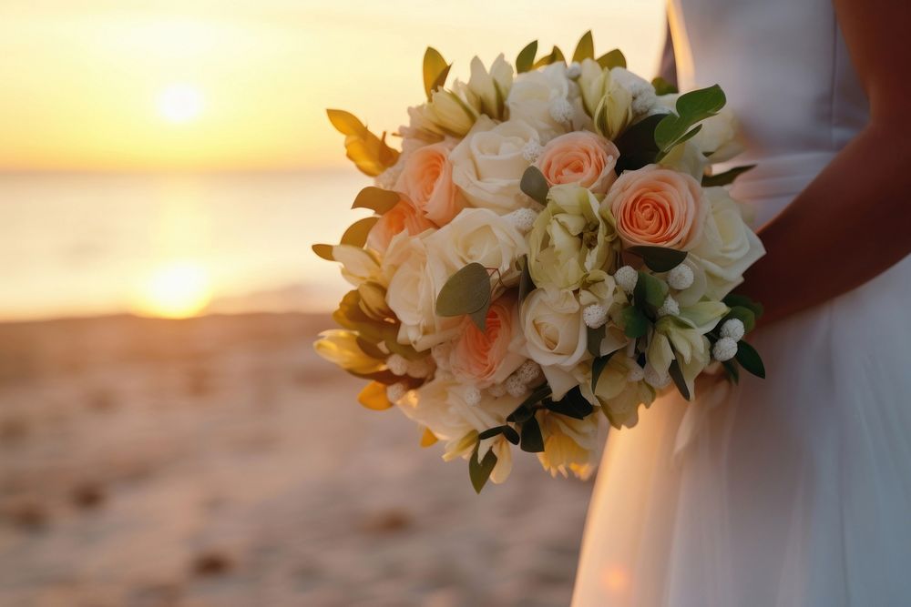 Closeup groom and bride have bouquet at the sunset beach, focus on bouquet.  