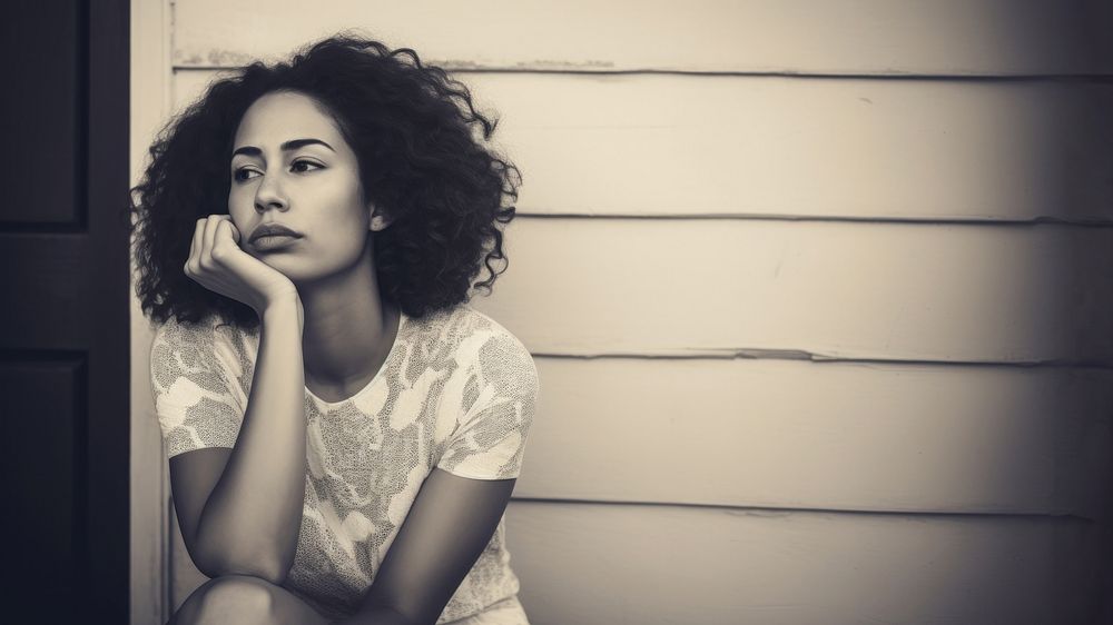 Authentic photo of mixed race woman is sitting and contemplating something.  