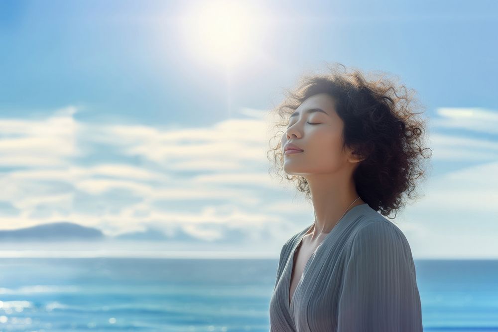 photo of woman praying with bluesky on the sea with blurred vision. AI generated Image by rawpixel. 