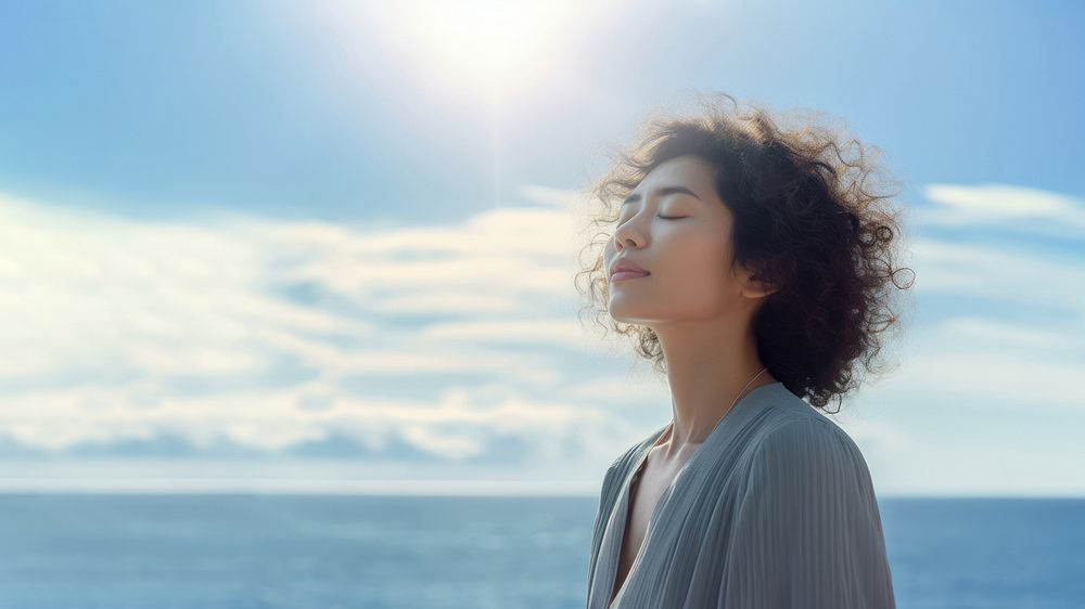 photo of woman praying with bluesky on the sea with blurred vision. AI generated Image by rawpixel. 