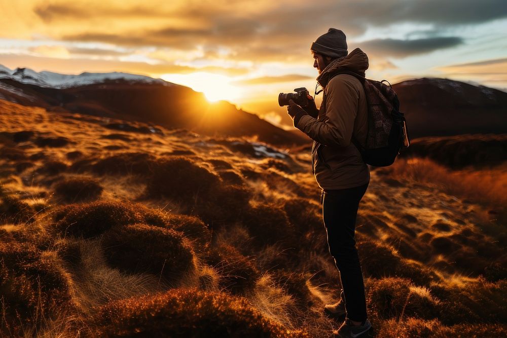 front-left view Photo of a man holding camera, taking picture in the wild in a chilly day. 