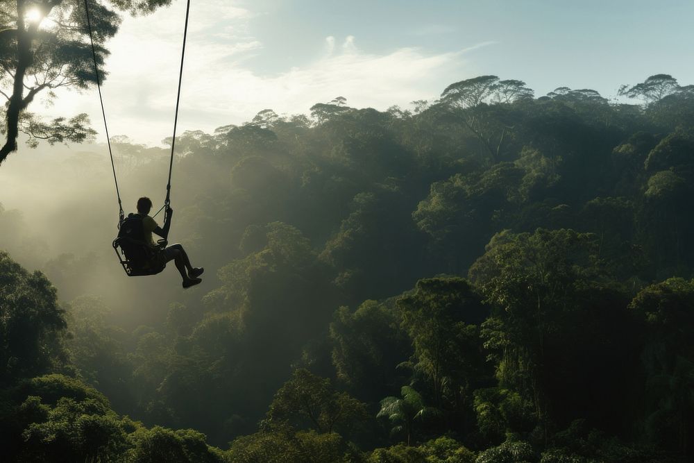 Photo of a man playing zipline through jungle. 