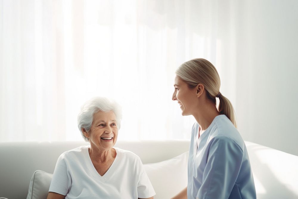 minimal, photo of staff caregiver talking to senior woman in hospital. 