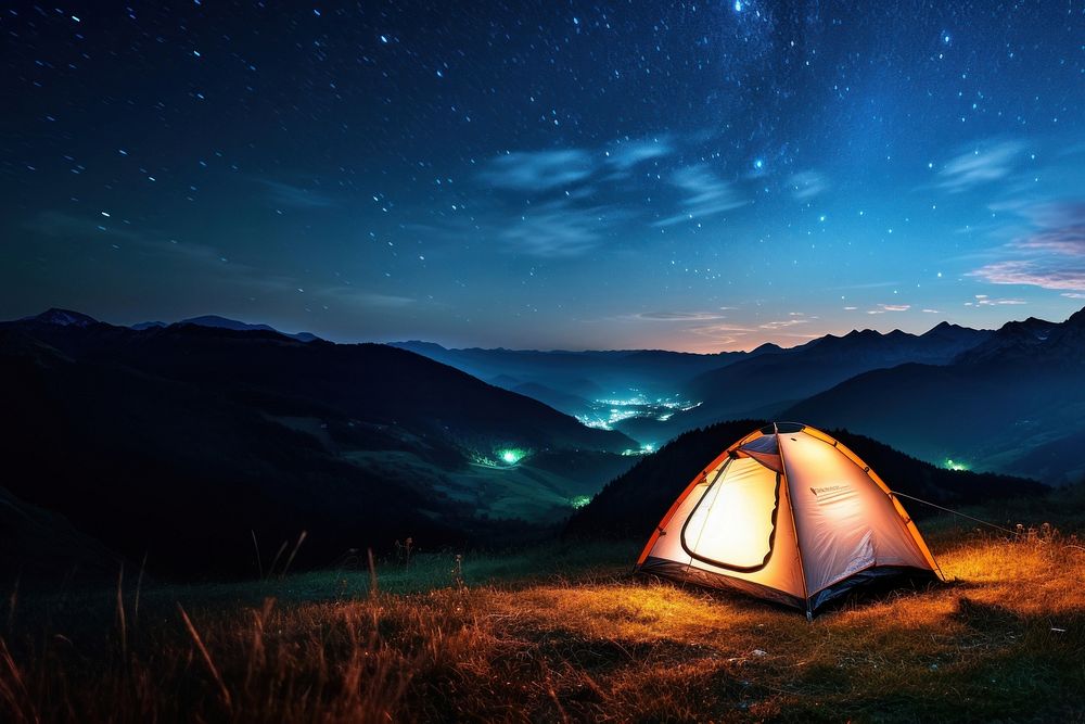 Photo of a tent, in a grass land, moutain in the background, at night, sky full of stars. AI generated Image by rawpixel.