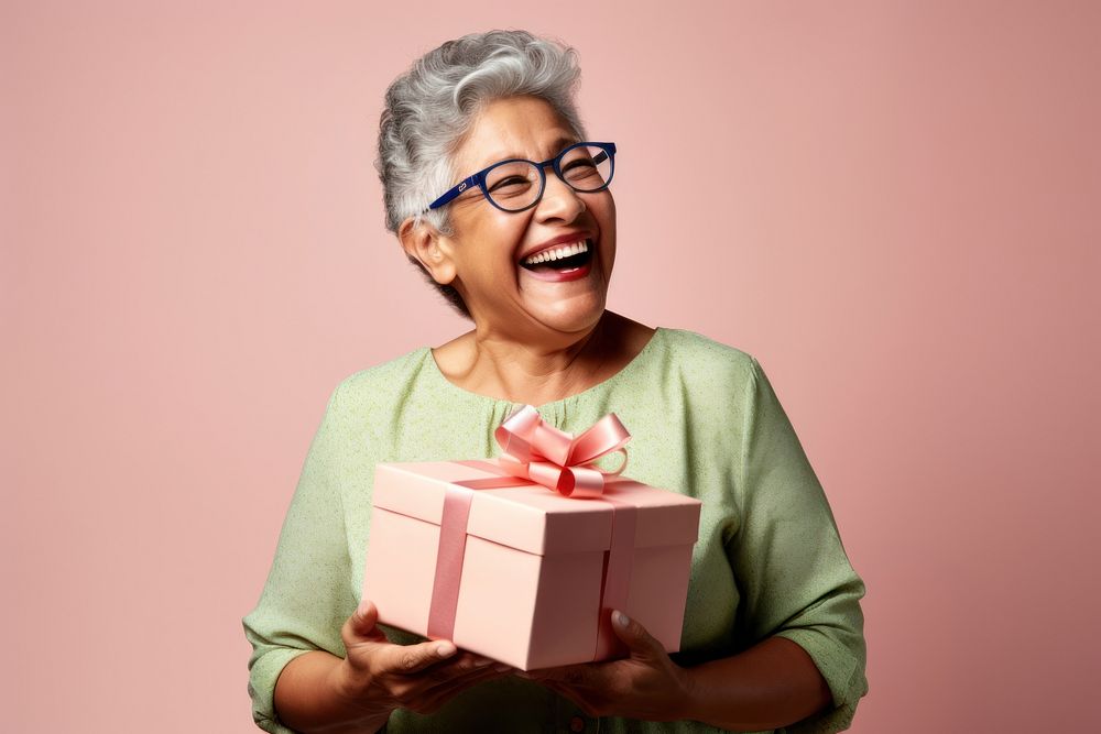 Chubby hispanic senior woman smiling hugging a gift box laughing birthday adult. AI generated Image by rawpixel.