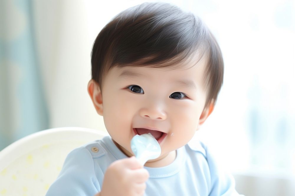 Baby eating spoon toothbrush innocence. AI generated Image by rawpixel.