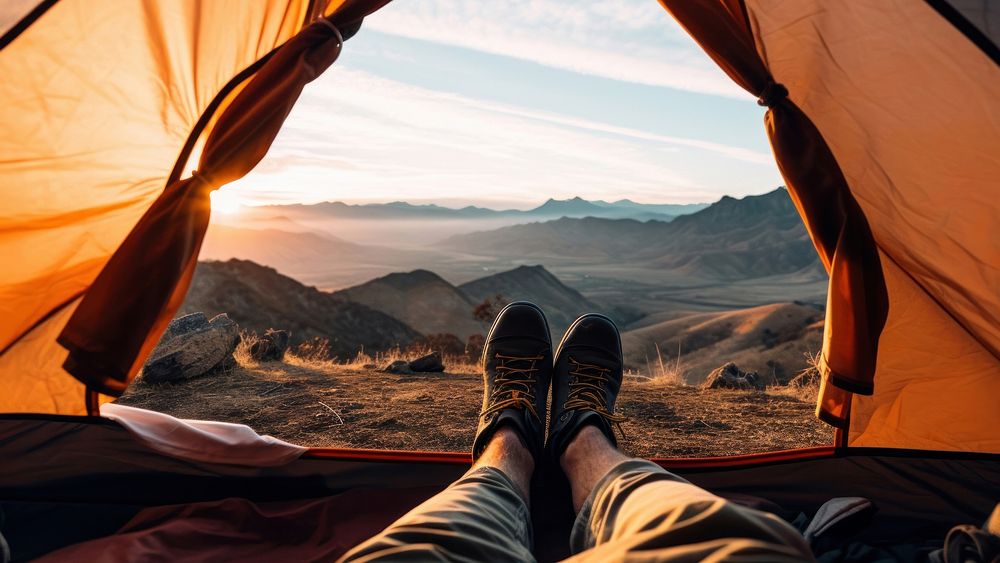 Photo of a foot of a man wearing boots stretching out of a tent, mountain view. AI generated Image by rawpixel. 