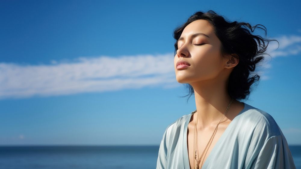 photo of woman praying with bluesky on the sea with blurred vision. AI generated Image by rawpixel. 