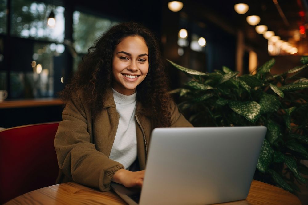 Hispanic woman using laptop smiling computer adult portability. AI generated Image by rawpixel.