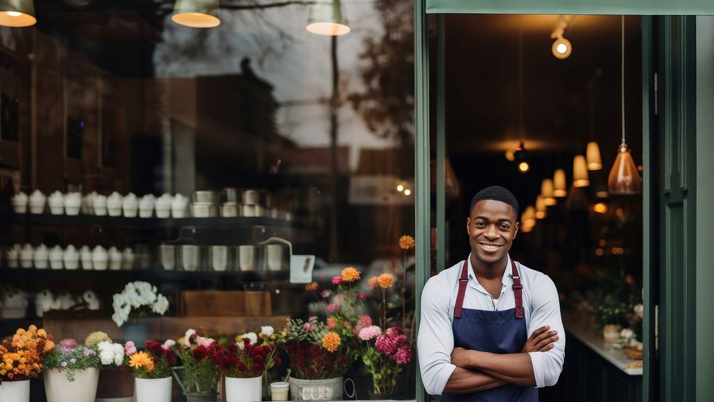 Photo of a cheerful small business owner standing and smiling in front of their shop. AI generated Image by rawpixel. 