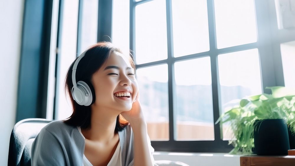 Photo of Asian woman smiling at home in headphones.  