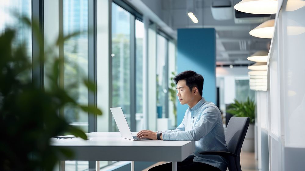 side view photo of an Asian office worker wearing casual clothes sitting in an office. AI generated Image by rawpixel. 