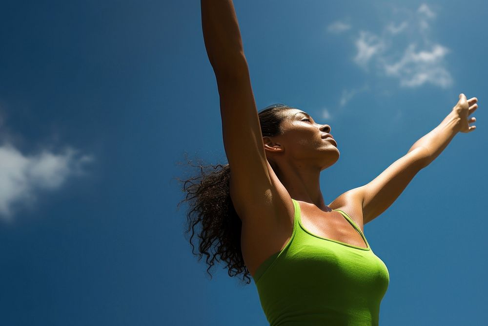 photo of mid-ages woman stretch the arms with bluesky and sun the green natual with blurred visio.  