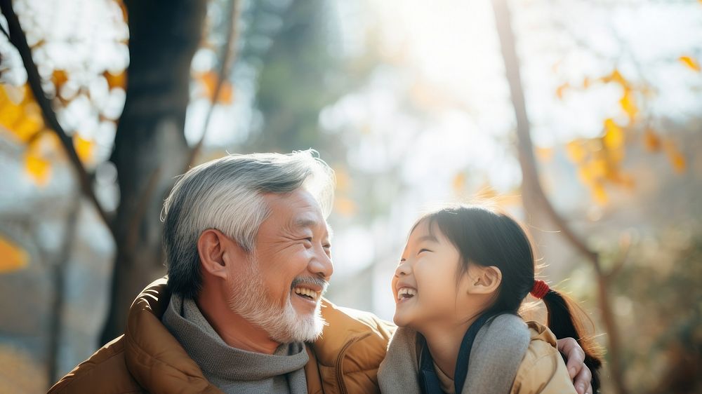 photo of Smiling happy older asian father with stylish short beard touching daughter's hand on shoulder looking and talking…