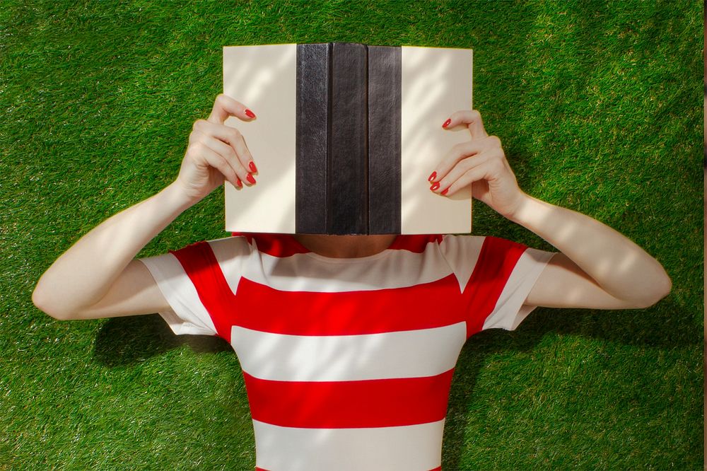 Woman reading book in park, tree branch shadow