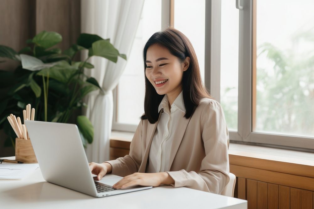 South east asian businesswoman computer sitting laptop. AI generated Image by rawpixel.