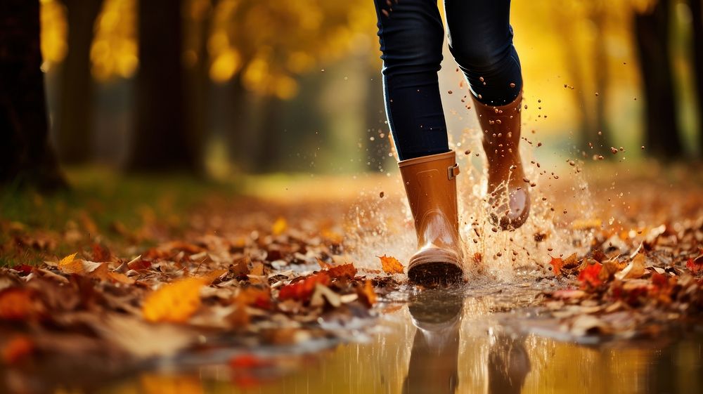 Woman legs wearing rain boots autumn puddle splashing. 