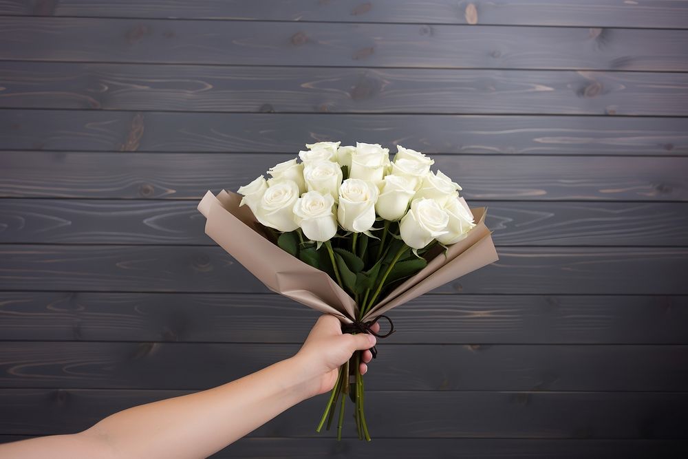 Hand holding white rose flower bouquet plant inflorescence arrangement. AI generated Image by rawpixel.