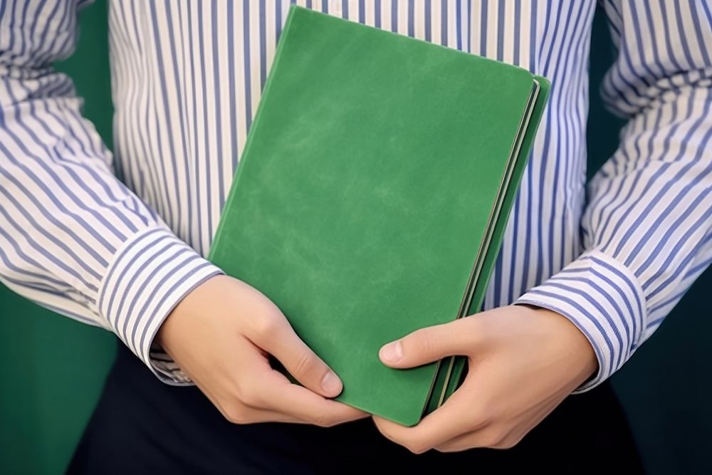 Stripes shirt man holding green book publication accessories midsection. AI generated Image by rawpixel.