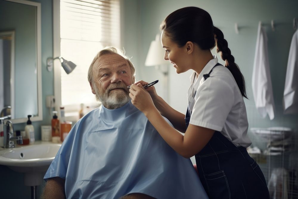 Female healthcare worker assisting senior man in shaving beard at bathroom mirror female adult hairdresser. AI generated…