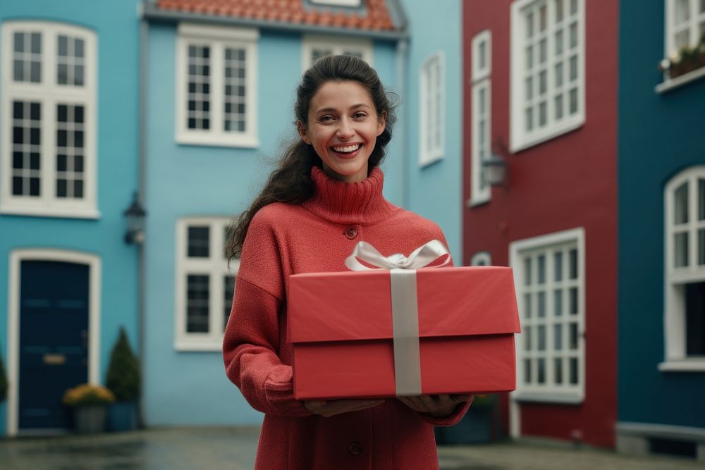 A woman carrying a large red gift box street architecture celebration. AI generated Image by rawpixel.