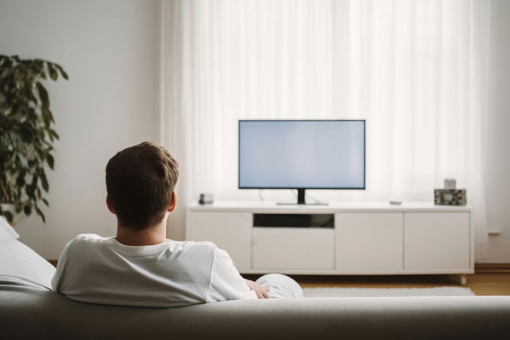 Man holding remote control and watching TV television furniture sitting. AI generated Image by rawpixel.
