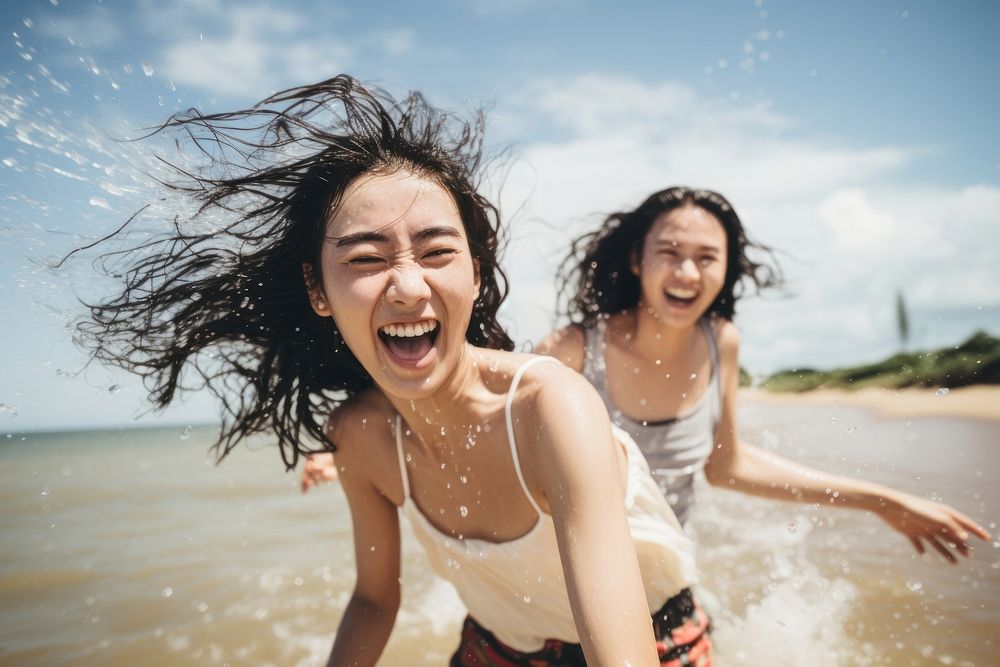 Thai teenage friends splashing laughing outdoors. AI generated Image by rawpixel.