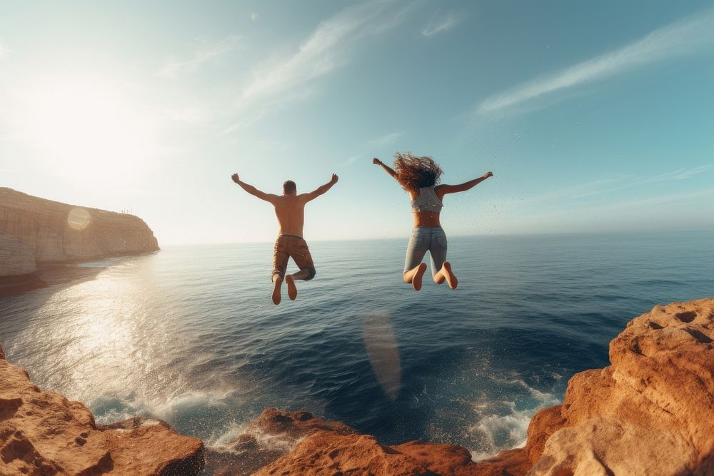 Two people jumping out of a cliff in front of transparent sea photography outdoors nature. AI generated Image by rawpixel.