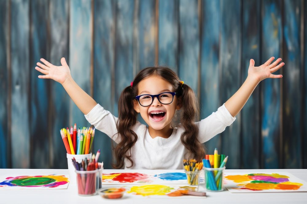 Little girl sitting at a table with stationery and paint child joy paintbrush. AI generated Image by rawpixel.