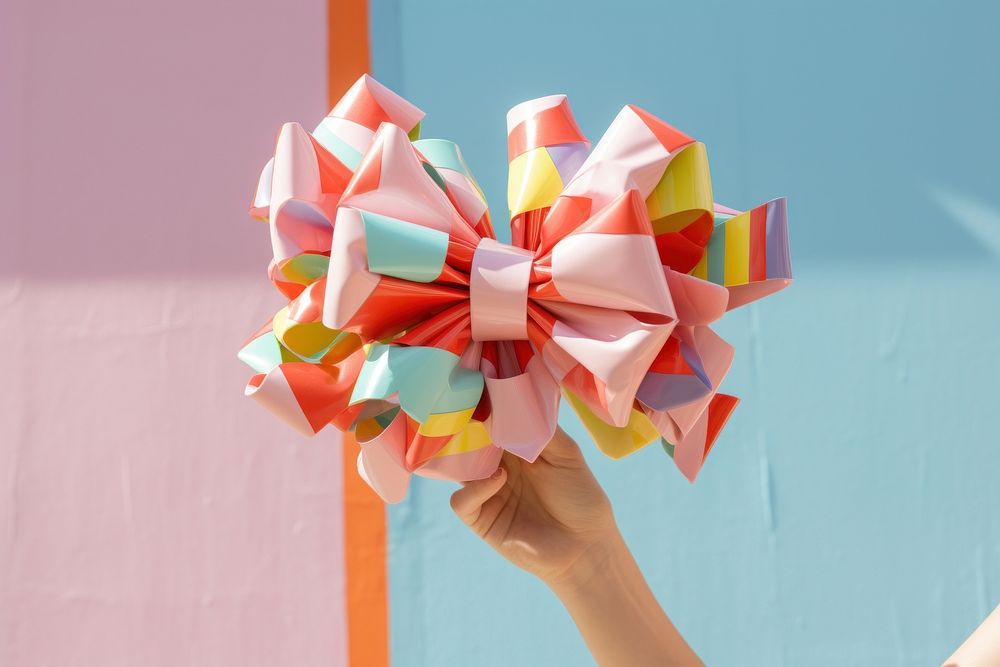 Hand holding big bow full color origami paper art. AI generated Image by rawpixel.
