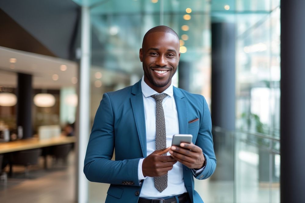 African Businessman standing with smart phone in office adult businesswear architecture. AI generated Image by rawpixel.
