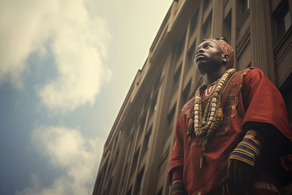 African man in a traditional costume lookingup the building in a big city portrait photo architecture. AI generated Image by…
