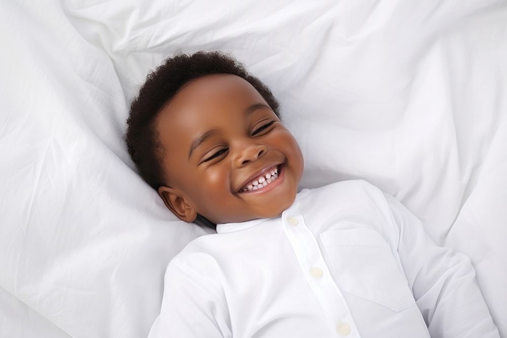 Smiling baby african boy lying on a bed sleeping on white sheets smiling smile comfortable. AI generated Image by rawpixel.