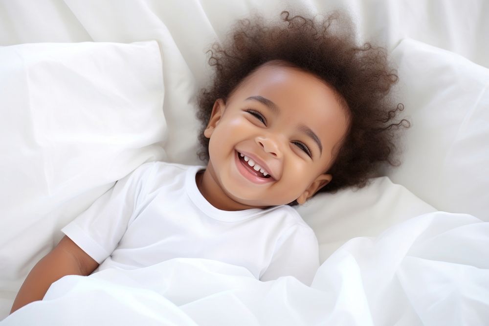Smiling baby african girl lying on a bed sleeping on white sheets smiling smile comfortable. AI generated Image by rawpixel.