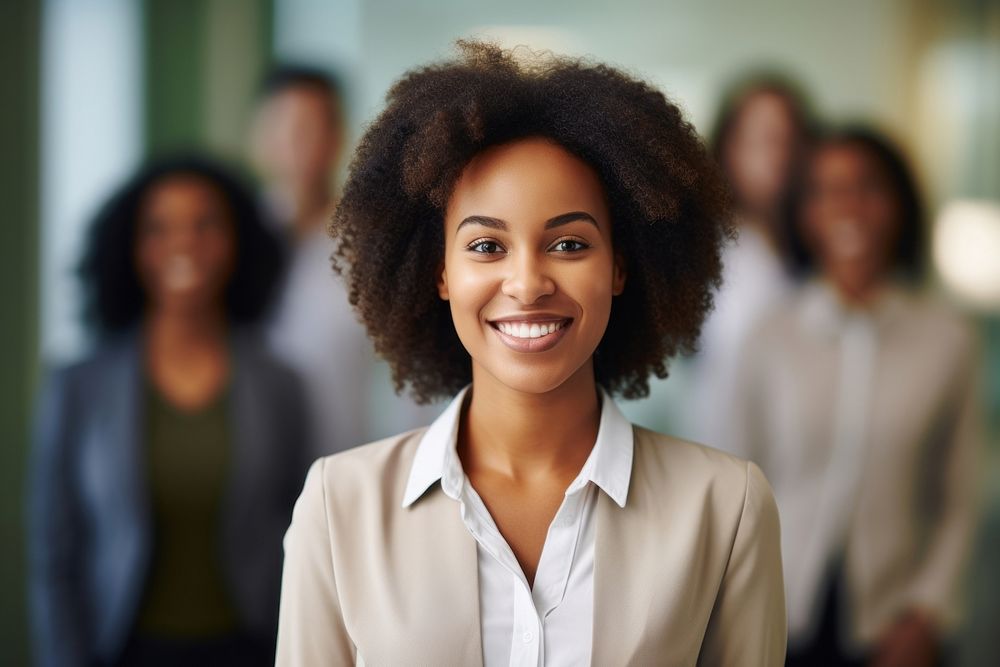 Smiling confident african business female leader looking at camera and standing in an office at team meeting smiling adult…