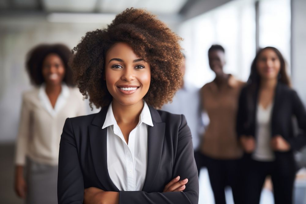 Smiling confident african business female leader looking at camera and standing in an office at team meeting smiling adult…