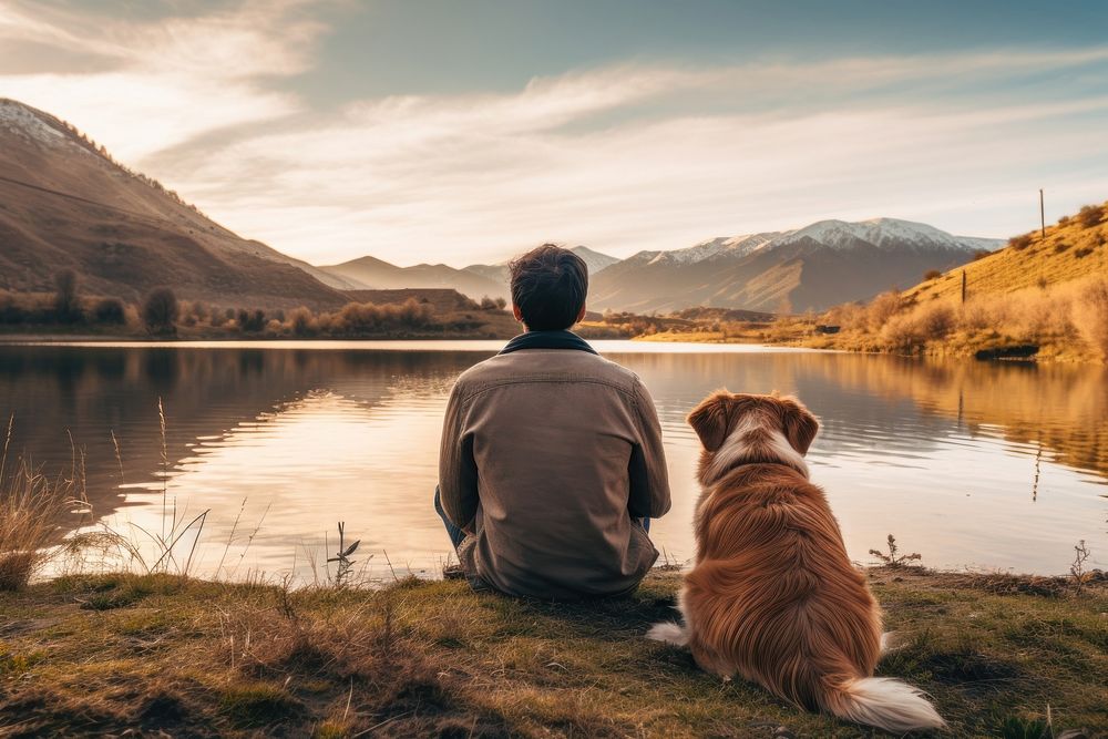 Latino man sitting in the lake side field with his dog landscape mountain outdoors. AI generated Image by rawpixel.