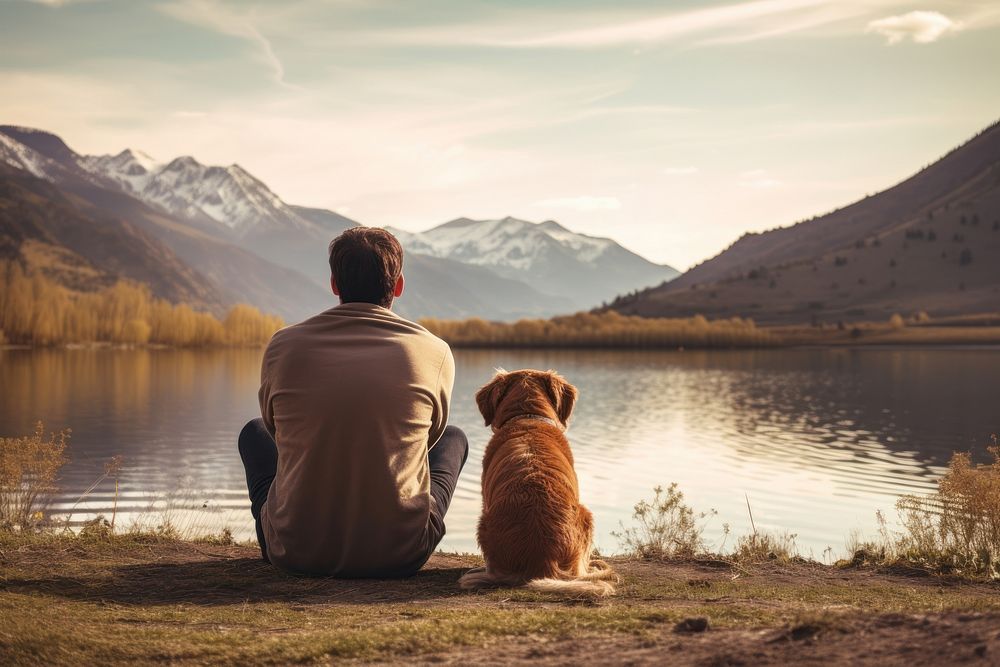 Latino man sitting in the lake side field with his dog landscape mountain outdoors. AI generated Image by rawpixel.