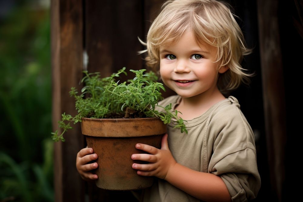 Kid in garden holding pot portrait outdoors smile. 