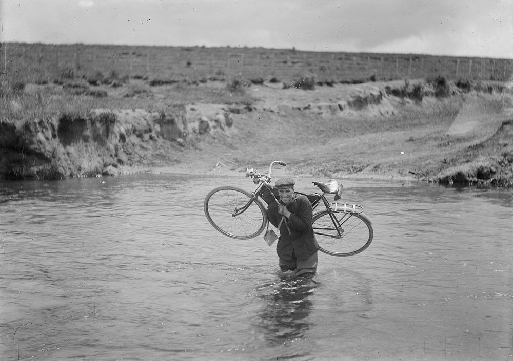 Fording a river, man holding a bicycle (1905) by Fred Brockett.