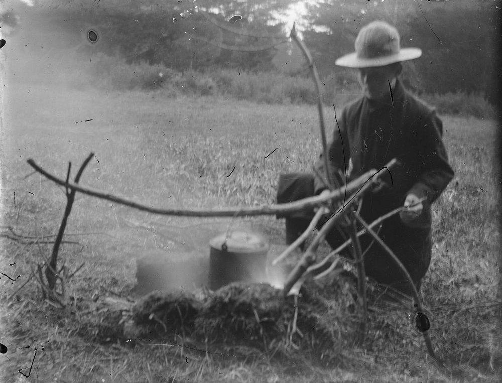 Man tending a campfire (1880-1925).