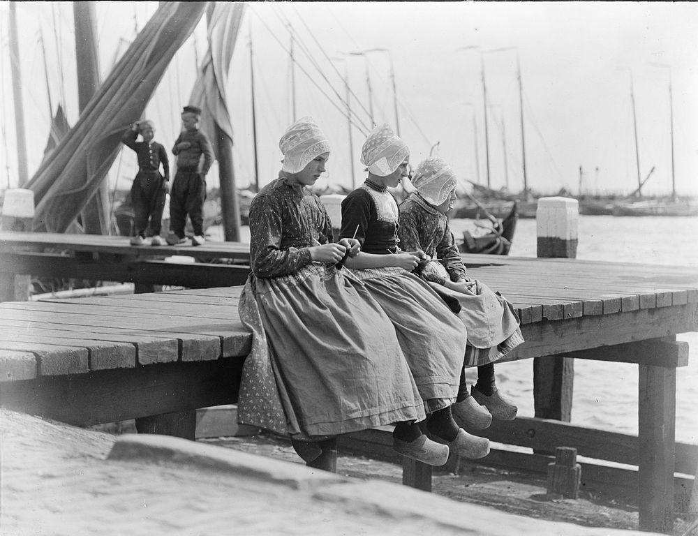 Three girls sitting on a dock, the Netherlands (1906-1917) by George Crombie.