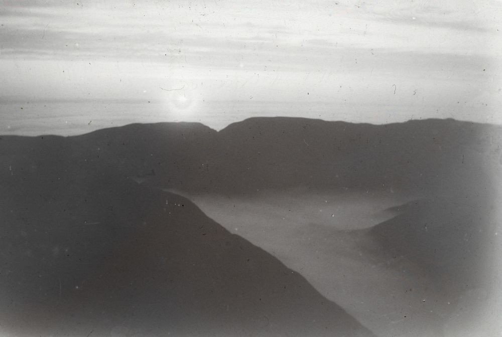 Early morning on Mt Dundas, the sun rising over edge of cloud sheet covering the Wairarapa ... (February 1909) by Leslie…