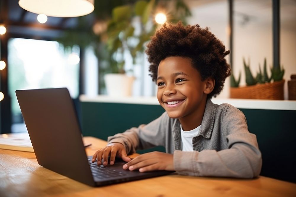 African American child schoolboy studying online laptop computer smiling. AI generated Image by rawpixel.