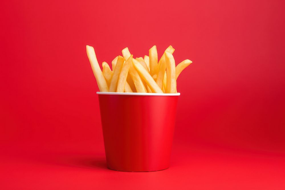 French fries in red paper cup food red background freshness. AI generated Image by rawpixel.