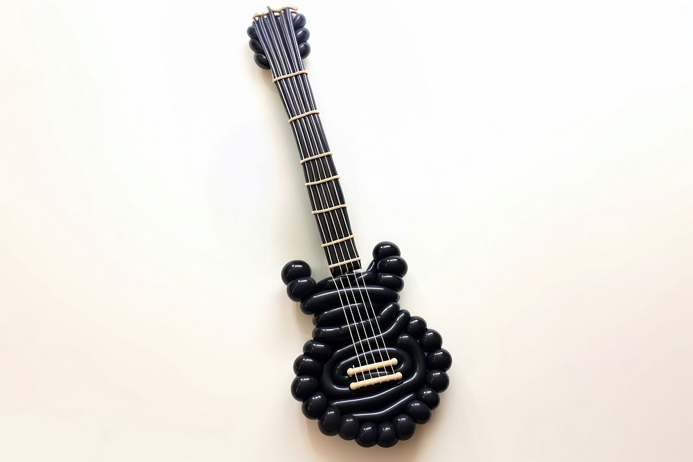 A balloon twisting in the shape of a guitar white background string music. 