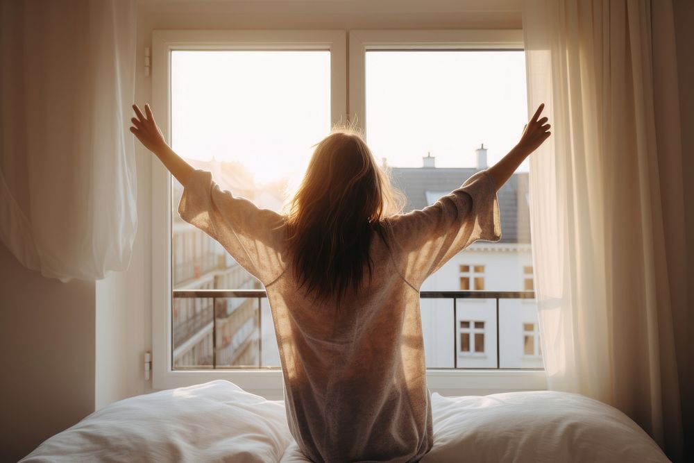 Woman wakes up window bed furniture. 