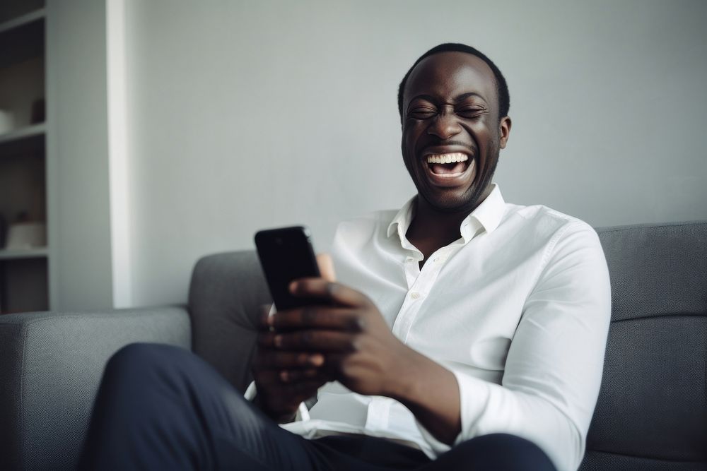 Happy relaxed african man using cell phone laughing smiling sitting. AI generated Image by rawpixel.