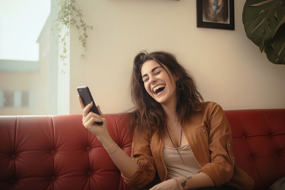 Happy relaxed young woman using cell phone laughing furniture smiling. AI generated Image by rawpixel.